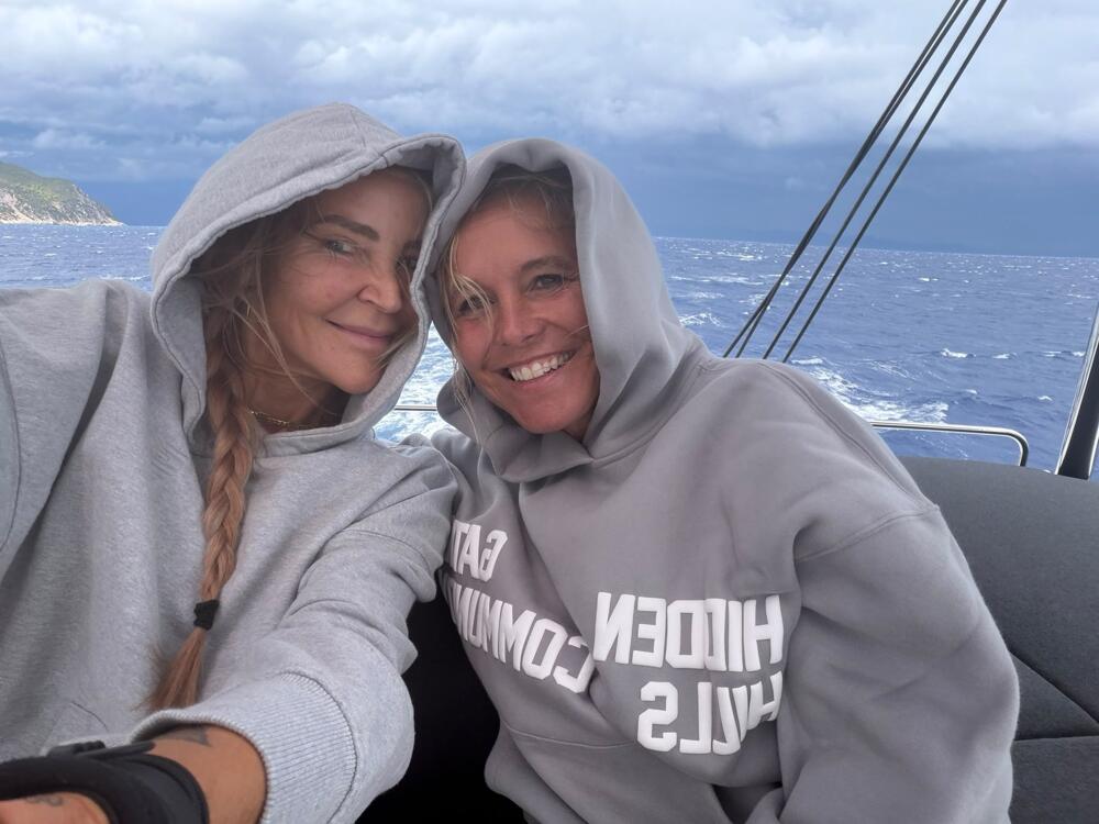 Fitchicks in hoodies sailing on the catamaran in Greece